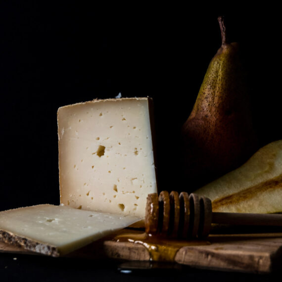 still life with pecorino cheese pears and honey on black background