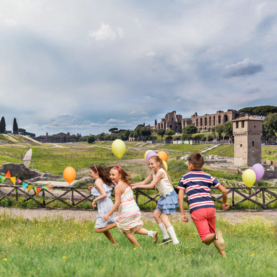 4 children chase each other with balloons during a birthday party at the Circus Maximus Rome